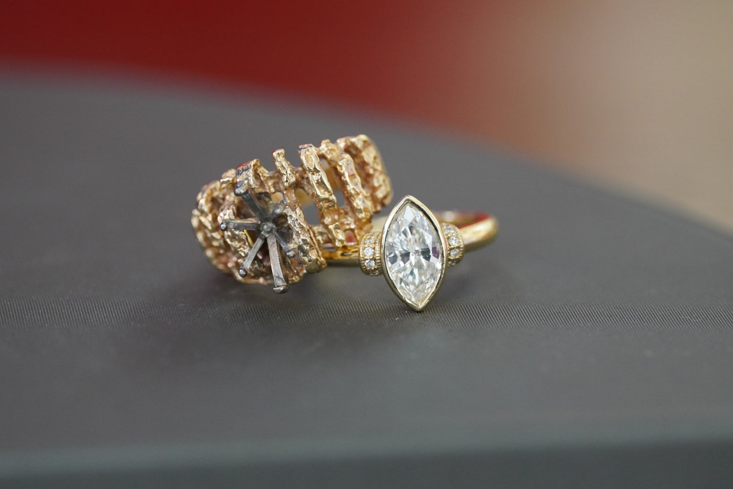 Two gold rings with gemstones on a dark surface