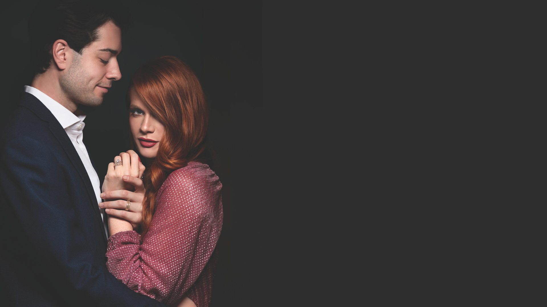 Man and woman holding hands against a dark background